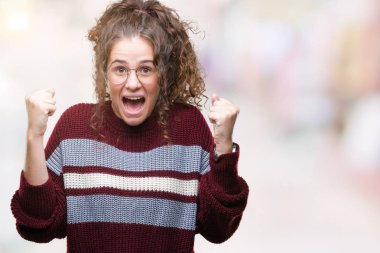 Güzel esmer kıvırcık saçlı Genç kız izole arka plan üzerinde kutluyor gözlük takan şaşırttı ve silah ile başarı için hayran kaldırdı ve gözleri açık. Kazanan kavramı.