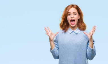 Genç güzel kadın çılgın kutlama kış kazak giyen ve silah ile başarı için heyecanlı çığlık kaldırdı ve açık gözleri hayret izole arka plan yüzünden. Kazanan kavramı