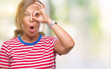 Orta yaş ok jest yapıyor izole arka plan üzerine İspanyol kadın kıdemli sürpriz yüz, göz parmaklarının arasından seyir ile şok. İmansız ifade.