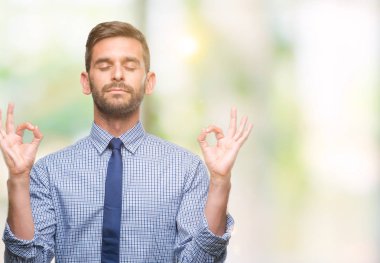 Genç yakışıklı iş adamı izole arka plan üzerinde dinlenmek ve gülümseyen gözlerle kapalı parmak jestle meditasyon yapıyor. Yoga kavramı.