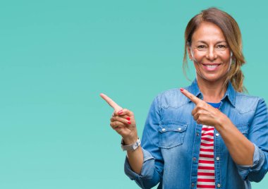 Orta yaş üst düzey İspanyol kadın gülümseyerek ve iki elleri ve parmakları ile tarafına işaret kamera bakarak izole arka plan.