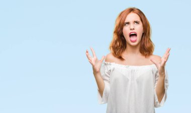 Genç güzel kadın izole arka plan çılgın ve kızgın bağırarak ve agresif ifade ve silah kaldırdı bağırıyor. Hayal kırıklığı kavramı.