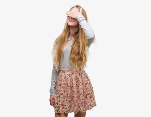 金发少女穿着花裙微笑和笑与手在脸上覆盖眼睛惊讶 盲概念 — 图库照片