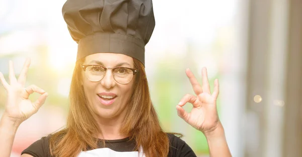 中年厨师的女人穿着主厨围裙做 标志手势双手表示冥想和放松 — 图库照片