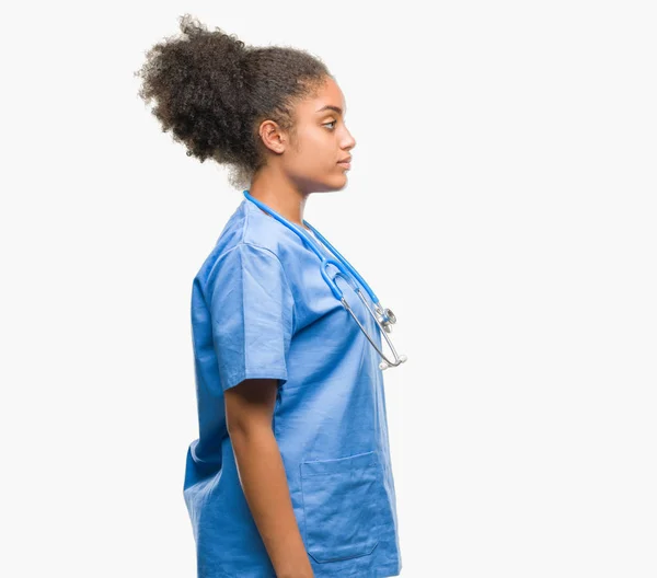 Young afro american doctor woman over isolated background looking to side, relax profile pose with natural face with confident smile.