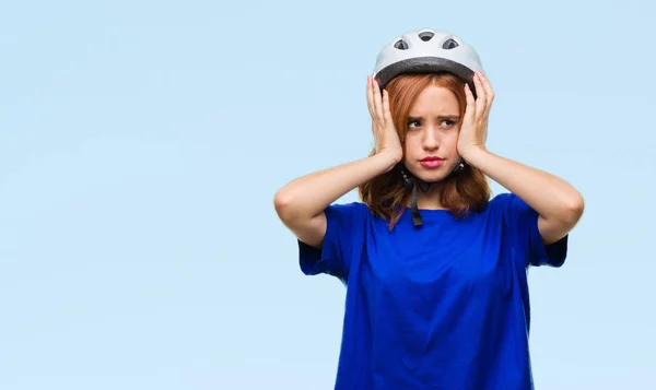 年轻漂亮的女人穿着自行车头盔在孤立的背景下患有头痛绝望和压力 因为疼痛和偏头痛 手在头上 — 图库照片