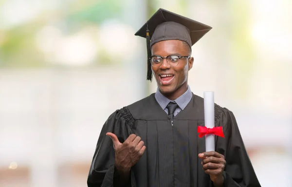 Giovane Laureato Afroamericano Uomo Possesso Laurea Sfondo Isolato Puntando Mostrando — Foto Stock