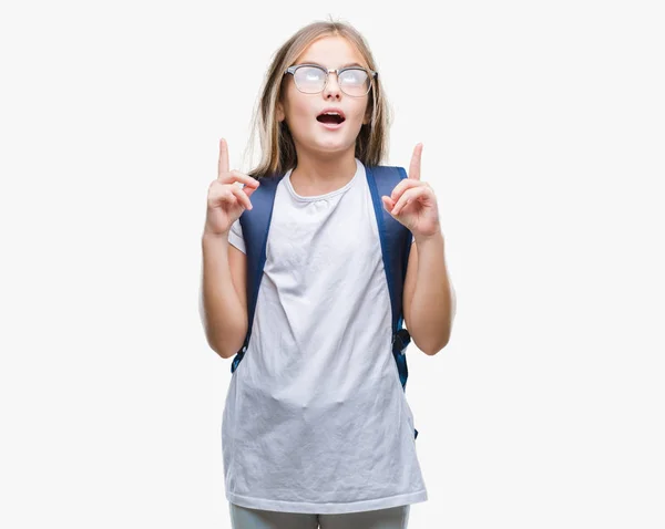 年轻漂亮聪明的学生女孩穿着背包在孤立的背景下惊讶和惊讶地看着手指和举起手臂 — 图库照片