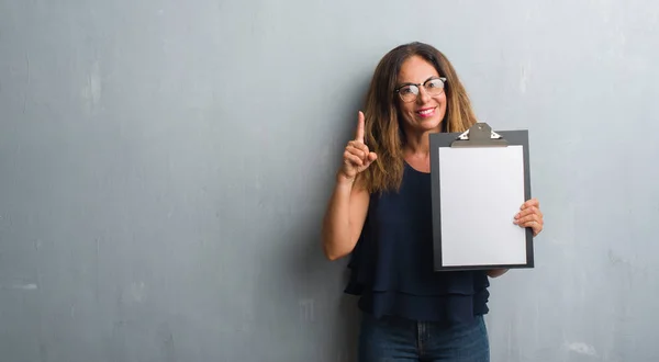 Middle Age Hispanic Woman Standing Grey Grunge Wall Holding Clipboard — Stock Photo, Image