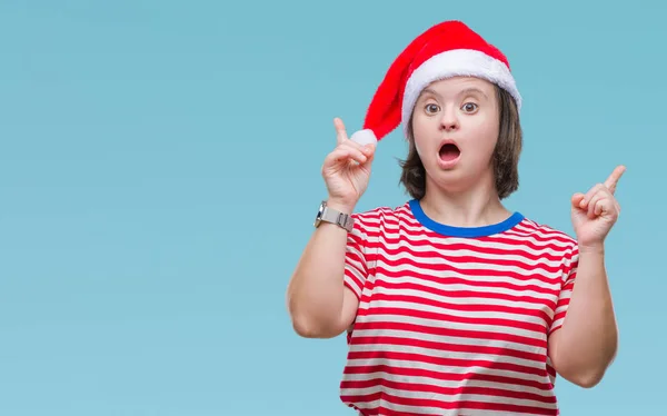 有唐氏综合症的年轻成年妇女戴着圣诞帽在孤立的背景下惊讶和惊讶地抬起手指 举起双臂 — 图库照片
