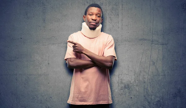 Injured african black man wearing neck brace pointing away side with finger