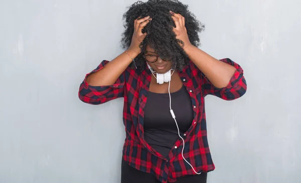 必死と強調した頭痛に苦しんでのヘッドフォンを身に着けている灰色のグランジの壁を越えて若いアフリカ系アメリカ人女性の痛みと片頭痛 頭に手 — ストック写真