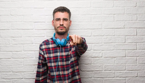 Homem Jovem Adulto Sobre Parede Tijolo Usando Fones Ouvido Apontando — Fotografia de Stock
