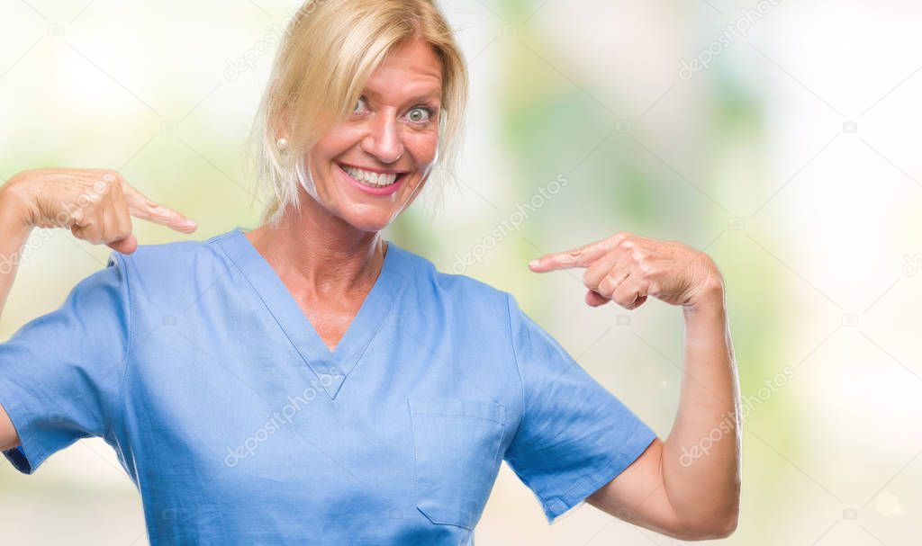 Middle age blonde woman wearing doctor nurse uniform over isolated background looking confident with smile on face, pointing oneself with fingers proud and happy.