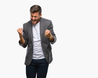 Gülümseyen ve başarı için çığlık genç yakışıklı iş adamı izole arka plan çok mutlu ve heyecanlı kaldırdı, silah ile kazanan jest yapıyor üzerinde. Kutlama kavramı.