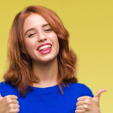 Genç güzel kadın el ile pozitif jest yapıyor izole arka plan başarı işareti yüzünden başparmak gülümseyen ve mutlu. Neşeli bir ifadeyle, kazanan jest kameraya bakıyor.