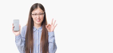 Genç Çinli kadın yüzünden arka plan gösteren kırık smartphone ekran parmak, mükemmel sembolü ile ok işareti yapıyor izole