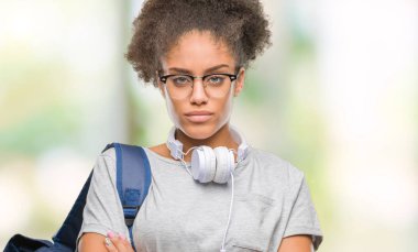 İzole arka plan şüpheci ve sinir, onaylamayan ifade yüz çapraz kolları üzerinde kulaklık ve sırt çantası giyen genç afro Amerikan öğrenci kadın. Negatif kişi.