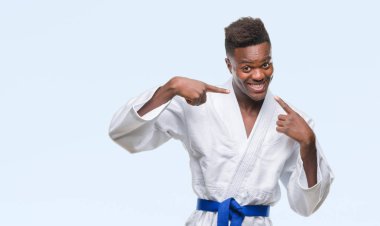 Afrikalı-Amerikalı genç kendinden emin gösterilen ve işaret parmakları diş ve ağız ile gülümseyen kimono giyen izole arka plan üzerinde. Sağlık kavramı.