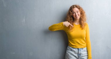 Gri grunge duvar sürpriz yüz işaret parmağı kendine genç Kızıl saçlı kadın