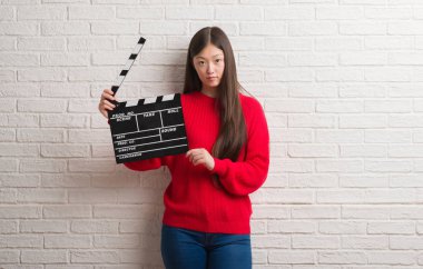 Kendinden emin bir ifade ile fıçı tahtası ciddi düşünme acımak yüz tutan beyaz tuğla duvarın üzerinden Genç Çinli kadın