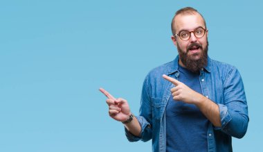 Gülümseyen ve iki elleri ve parmakları ile tarafına işaret kamera bakarak izole arka plan üzerinde gözlük takan Genç beyaz hipster adam.