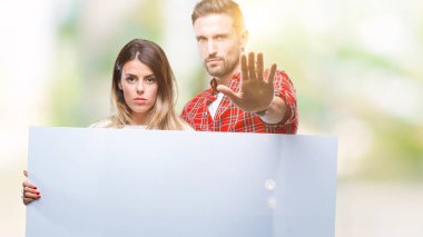 Genç çift izole arka plan üzerinde açık eliyle dur işareti ile ciddi ve kendine güvenen ifade, savunma jest yapıyor boş afiş bir arada tutan