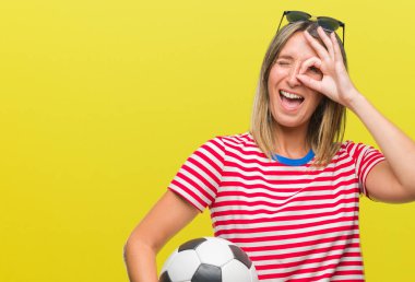 Mutlu yüz el parmaklarının arasından seyir göz üzerinde ok işaretiyle yapıyor gülümseyen izole arka plan üzerinde futbol futbol topu tutan genç güzel kadın