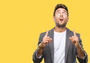 Genç yakışıklı iş adamı izole arka plan üzerinden hayran ve yukarıya bakıp parmakları ile işaret şaşırttı ve silah kaldırdı.