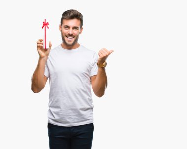 İşaret ve başparmak kadar mutlu yüz gülümseyen tarafı ile gösteren izole arka plan üzerinde Sevgililer günü hediyesi veren aşık genç yakışıklı adam