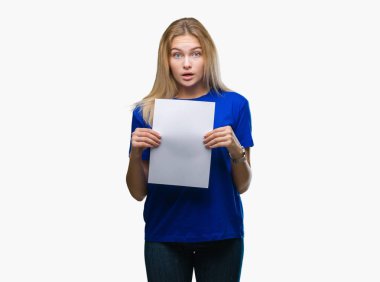 Kafkasyalı genç bir kadın izole edilmiş arka planda boş kâğıt çarşaf tutuyor. Şaşırmış bir yüz ifadesinden korkuyor ve heyecanlanıyor.