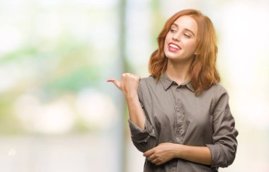 Seyir ve başparmak yanında yukarıyı mutlu yüz ile gülümseyen izole arka plan üzerinde genç güzel kadın.