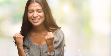 Gülümseyen ve başarı için çığlık genç güzel Arap kadın izole arka plan çok mutlu ve heyecanlı kaldırdı, silah ile kazanan jest yapıyor. Kutlama kavramı.