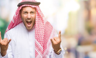 Keffiyeh deli ifade rock simge elle yapıyor ile bağırarak izole arka plan üzerinde giyen genç yakışıklı adam. Müzik yıldızı. Ağır kavramı.