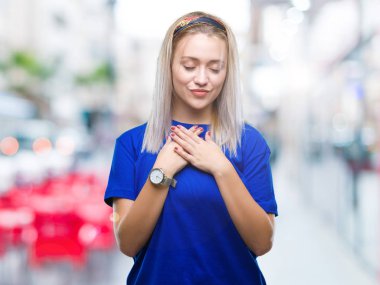 Sarışın genç kadın ile gülümseyen izole arka plan üzerinde kapalı gözler ve yüzünde minnettar jest ile göğüs üzerinde eller. Sağlık kavramı.