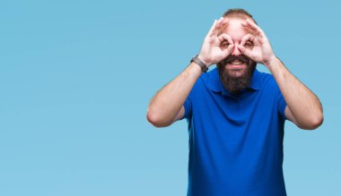 Dilini, parmaklarının arasından baktığını yapışmasını dürbün gibi ok jest yapıyor izole arka plan üzerinde mavi gömlek giymiş genç beyaz hipster adam. Deli ifade.