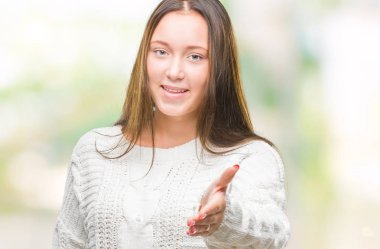 Üzerinde kış kazak giyen genç güzel beyaz kadın arka plan dostu sunan karşılıklı tebrik ve davet edici gülümseyen izole. Başarılı iş.