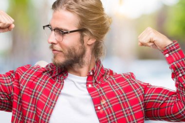 Genç yakışıklı adam uzun saçlı gözlüklü gururlu gülümseyen kol kasları gösterilen izole arka plan üzerinde. Fitness kavramı.