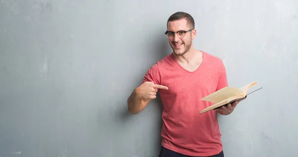 Jovem Caucasiano Sobre Parede Grunge Cinza Lendo Livro Muito Feliz — Fotografia de Stock