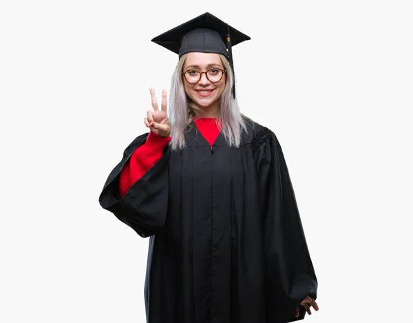 若いブロンドの女性の上の大学院の制服を着て分離で背景が表示され 自信を持って 幸せな笑みを浮かべている間 つ番号を指で上向き — ストック写真