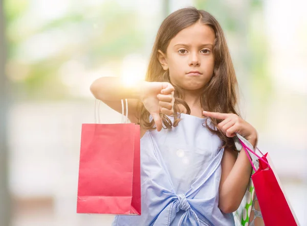 怒った顔 ダウン親指で嫌悪感を示すマイナス記号 拒絶反応の概念と買い物袋を保持しているヒスパニックのブルネットの少女 — ストック写真