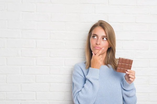 Hermosa Mujer Joven Sobre Pared Ladrillo Blanco Comiendo Barra Chocolate —  Fotos de Stock