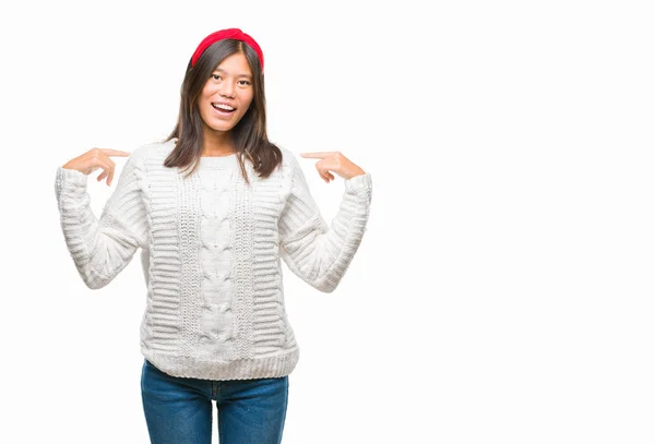 若いアジア女性の顔に笑顔と自信を持って 誇りと幸せな指で自分を指している孤立した背景に冬のセーターを着て — ストック写真
