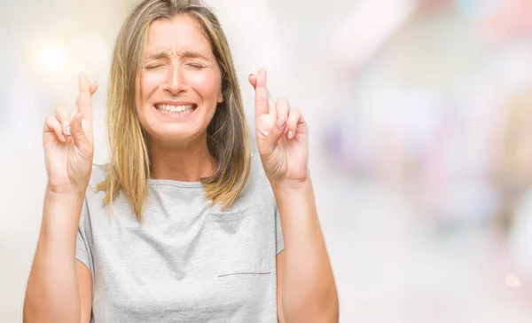 年轻美丽的女人在孤立的背景下微笑交叉手指与希望和眼睛关闭 运气和迷信概念 — 图库照片