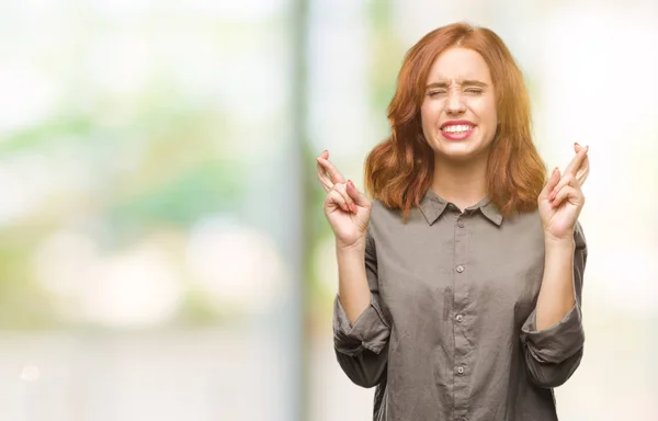 年轻美丽的女人在孤立的背景下微笑交叉手指与希望和眼睛关闭 运气和迷信概念 — 图库照片