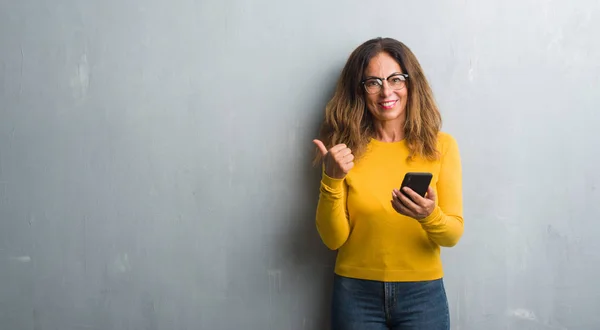 Mulher Hispânica Meia Idade Usando Smartphone Apontando Mostrando Com Polegar — Fotografia de Stock