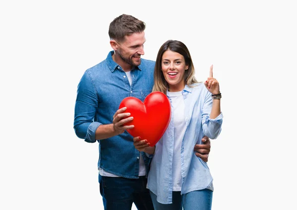 Jovem Casal Apaixonado Segurando Coração Vermelho Sobre Fundo Isolado Surpreso — Fotografia de Stock