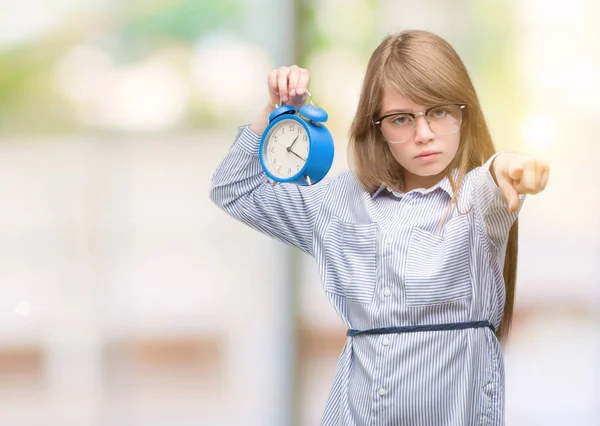 Young Blonde Child Holding Alarm Clock Pointing Finger Camera You — Stock Photo, Image