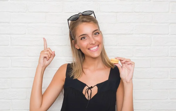 Beautiful Young Woman White Brick Wall Eating Yellow Macaron Surprised — Stock Photo, Image