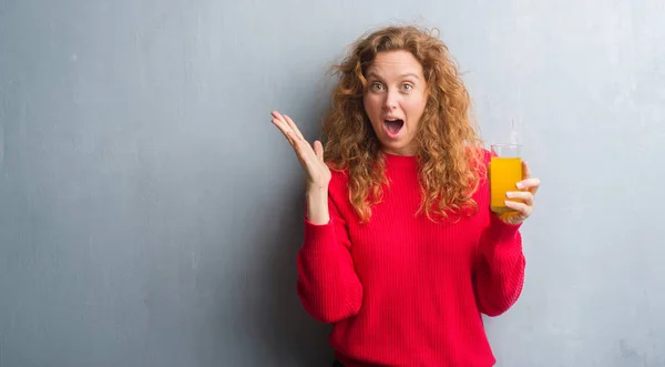 Joven Pelirroja Sobre Pared Gris Grunge Bebiendo Vaso Jugo Naranja — Foto de Stock